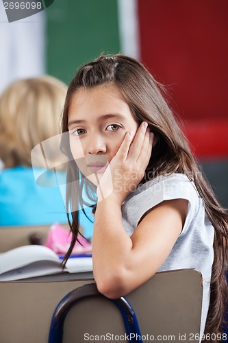 Image of Schoolgirl Leaning On Chair In Classroom