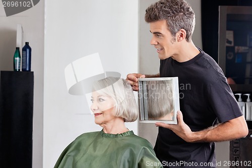 Image of Hairstylist Showing Finished Haircut To Customer At Parlor