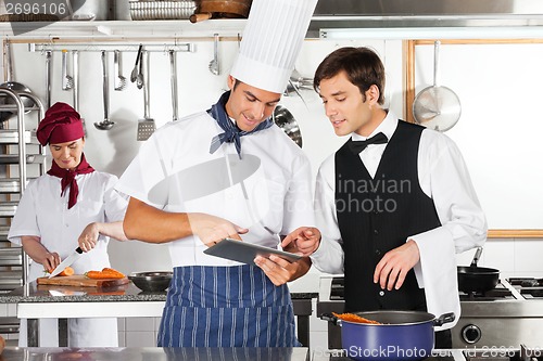 Image of Waiter And Chef Using Digital Tablet In Kitchen