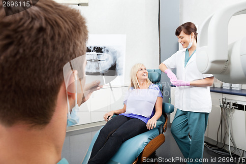 Image of Dentist Examining X-Ray Image With Female Assistant Communicatin