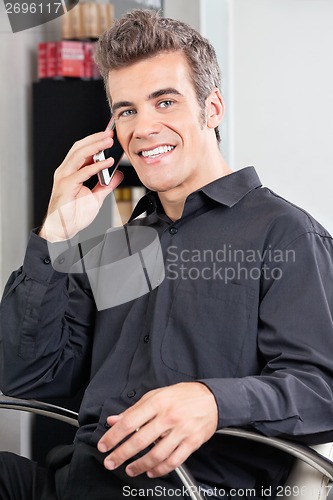 Image of Male Customer Using Cellphone At Salon