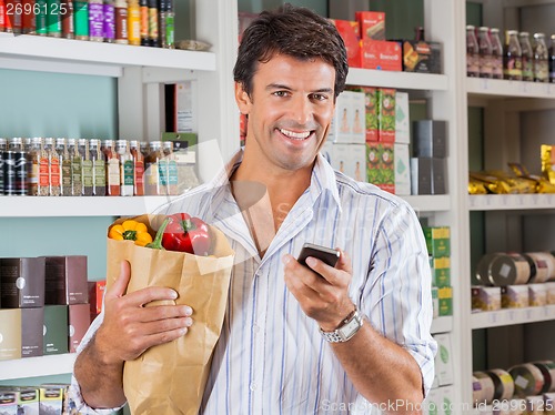 Image of Man With Mobile Phone And Grocery Paper Bag
