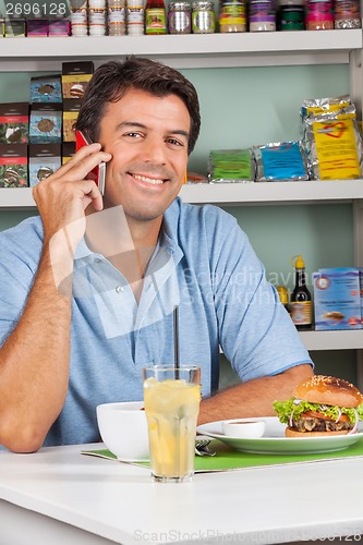 Image of Man Using Cellphone At Table In Supermarket