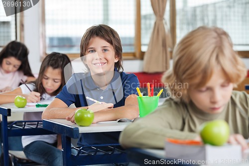 Image of Schoolboy Sitting At Desk With Classmates In A Row