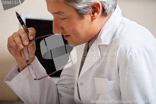 Image of Doctor Holding Pen And Glasses