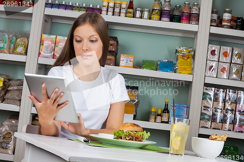 Image of Woman Using Tablet While Having Snacks In Supermarket