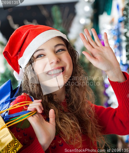 Image of Woman Waving While Carrying Shopping Bags At Christmas Store