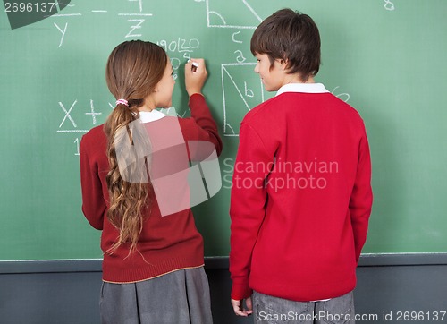 Image of Students Looking At Each Other While Writing On Board