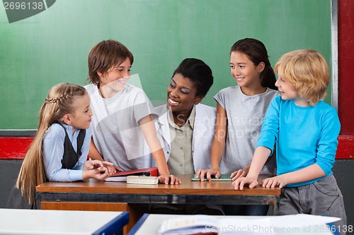 Image of Happy Teacher With Students Communicating At Desk