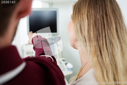 Image of Man Showing Ultrasound Machine To Woman
