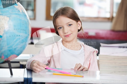 Image of Schoolgirl Smiling With Books And Globe At Desk