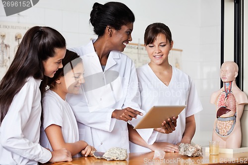 Image of Teacher Using Digital Tablet With Students At Desk