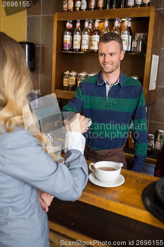 Image of Bartender Holding Card-Reader While Woman Making Payment Through