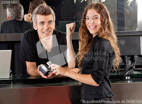 Image of Happy Woman Paying Through Cellphone At Salon Counter