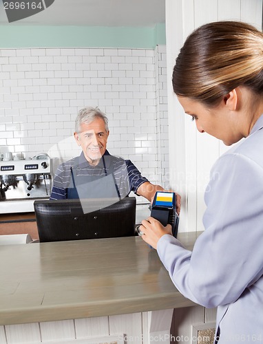 Image of Woman Making Payment Through Mobilephone At Counter