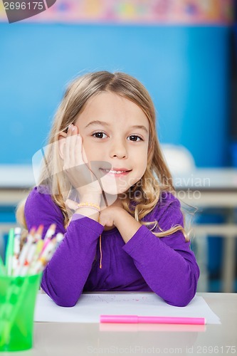 Image of Cute Girl Sitting With Hand On Chin At Desk