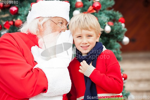 Image of Santa Claus Whispering In Boy's Ear