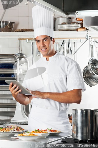 Image of Young Chef Holding Tablet With Pasta Dishes At Counter