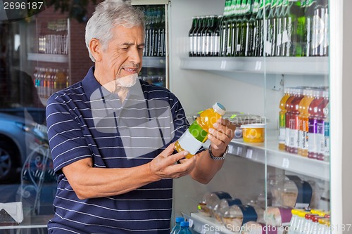 Image of Man Reading Information On Juice Bottle