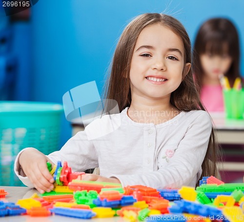 Image of Girl Playing With Construction Blocks With Friends In Background