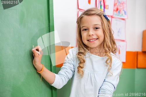 Image of Cute Girl Writing On Board In Kindergarten