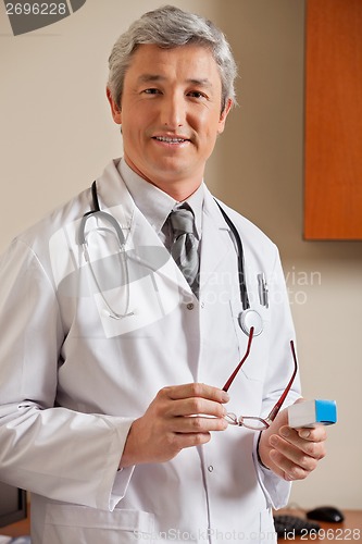 Image of Doctor Holding Glasses And Medicine Box