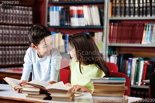 Image of Happy Schoolgirls Looking At Each Other While Studying In Librar