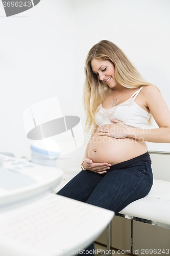 Image of Pregnant Woman Caressing Belly In Clinic