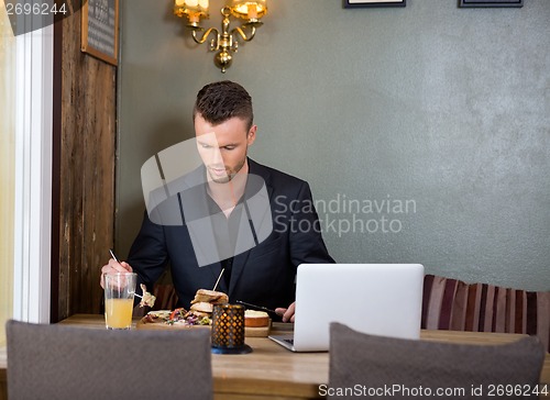 Image of Businessman Having Sandwich At Restaurant