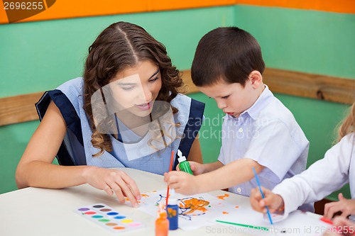 Image of Boy Painting While Teacher Assisting Him