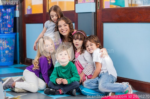 Image of Teacher And Students Sitting Together On Floor