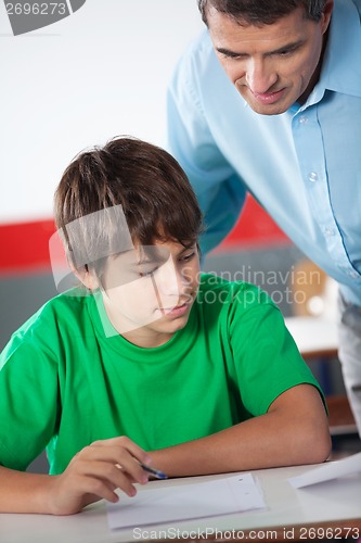 Image of Mature Professor Assisting Teenage Boy At Desk