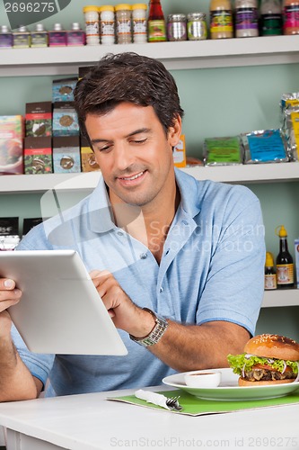 Image of Male Customer With Snacks Using Digital Tablet In Store