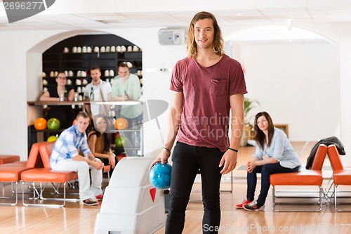 Image of Young Man Holding Ball in Bowling Alley At Club