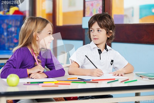 Image of Boy Looking At Female Friend While Drawing In Classroom