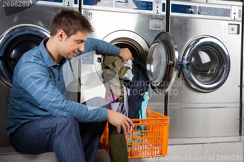 Image of Man Putting Clothes In Washing Machine