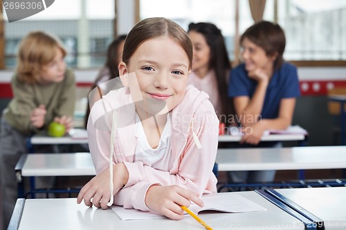 Image of Schoolgirl Smiling While Leaning On Desk