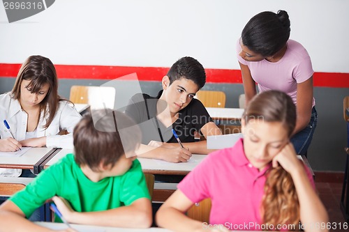 Image of Teacher Assisting Teenage Schoolboy During Examination