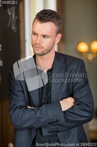 Image of Thoughtful Businessman Standing Arms Crossed In Coffeeshop