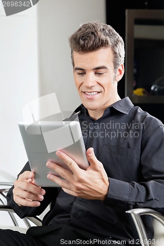 Image of Male Client Using Digital Tablet In Salon