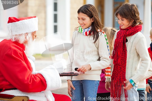 Image of Santa Claus Offering Biscuits And Milk To Children