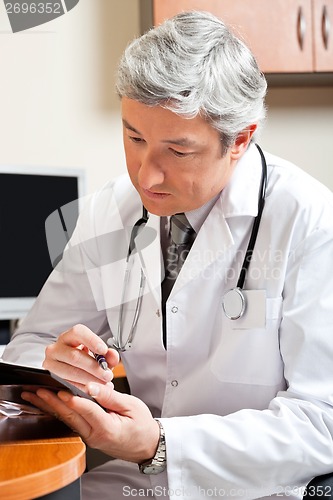 Image of Mature Doctor Reading At Desk