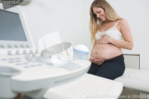 Image of Woman Holding Tummy By Ultrasound Machine