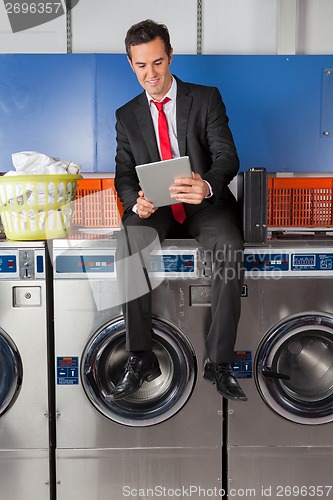 Image of Businessman Using Digital Tablet In Laundry