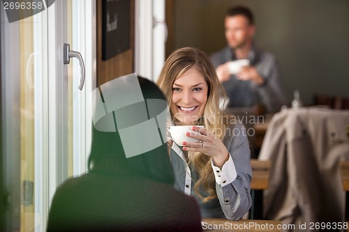 Image of Young Woman With Friend Having Coffee At Cafe