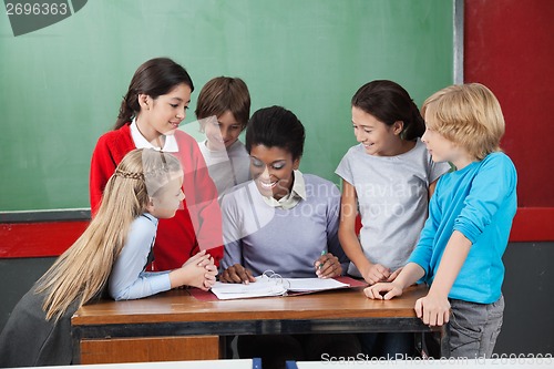 Image of Female Teacher Teaching Schoolchildren At Desk