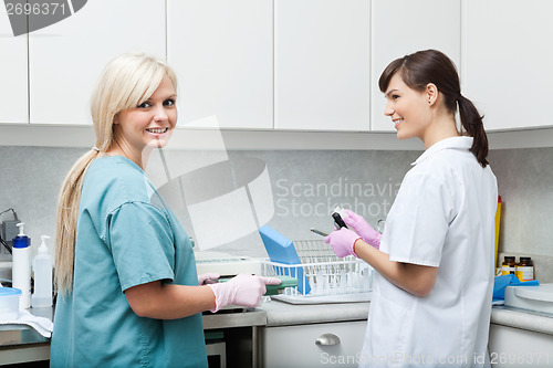 Image of Smiling Dentist With Assistant Cleaning Medical Instruments At C