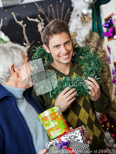 Image of Man Holding Wreath Standing With Father At Christmas Store