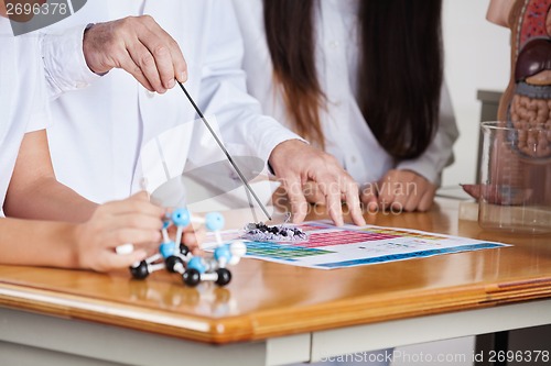 Image of Male Teacher With Students Experimenting At Desk