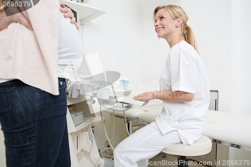 Image of Doctor Using Ultrasound Machine While Looking At Pregnant Woman